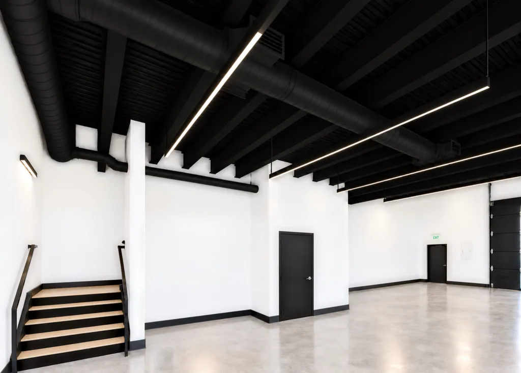 Suite ground floor with polished concrete, black ceiling and ductwork, a stair, interior doors and an overhead door